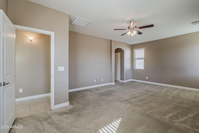 empty room featuring arched walkways, visible vents, light carpet, ceiling fan, and baseboards