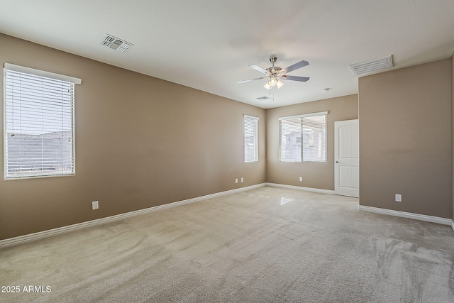 empty room with baseboards, visible vents, a ceiling fan, and light colored carpet