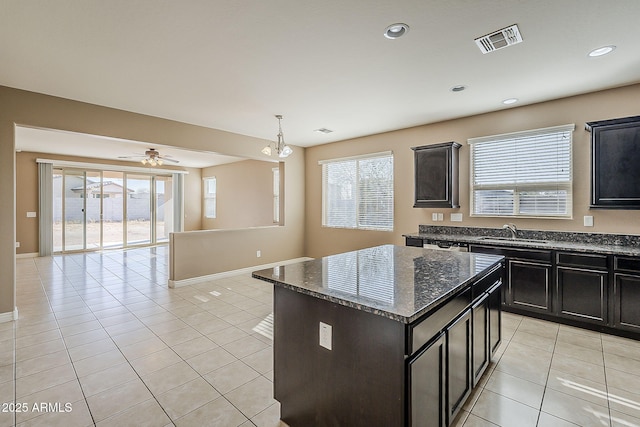 kitchen with light tile patterned floors, a sink, visible vents, open floor plan, and dark stone countertops