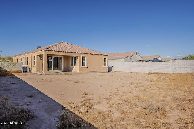 rear view of house featuring central AC, fence, a tiled roof, and stucco siding