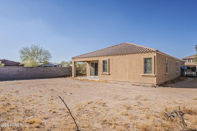 rear view of property with a tile roof, a fenced backyard, and stucco siding