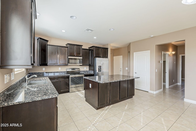 kitchen featuring a kitchen island, a sink, visible vents, appliances with stainless steel finishes, and dark stone countertops