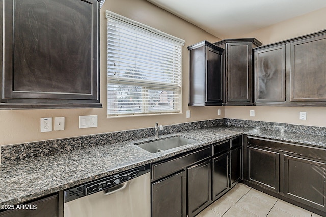 kitchen featuring light tile patterned floors, dark stone counters, a sink, dark brown cabinets, and dishwasher