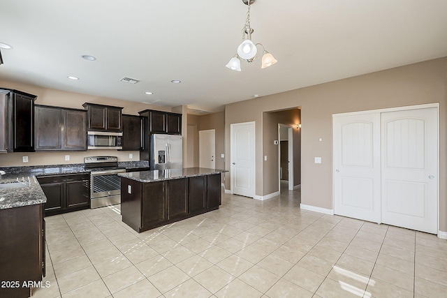 kitchen featuring stainless steel appliances, visible vents, light tile patterned flooring, a kitchen island, and dark stone counters