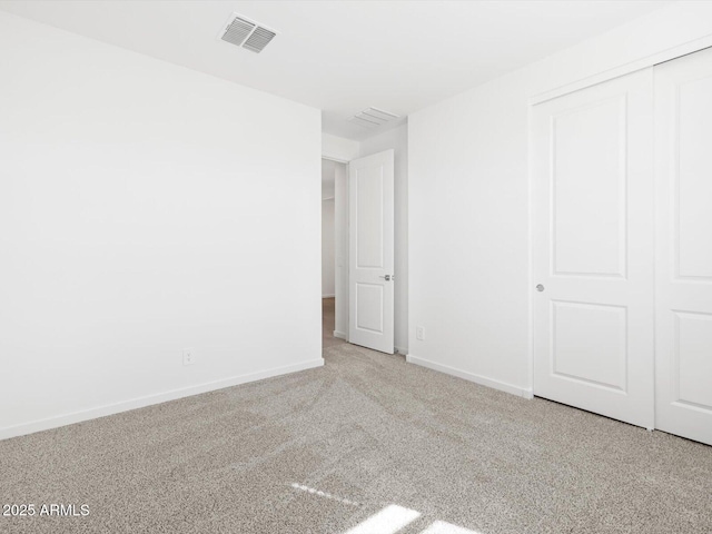 unfurnished bedroom with a closet, carpet, visible vents, and baseboards