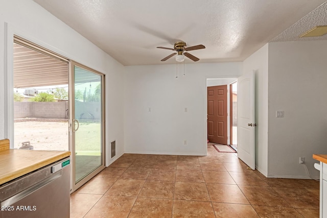 unfurnished room with a textured ceiling, a ceiling fan, baseboards, light tile patterned floors, and visible vents