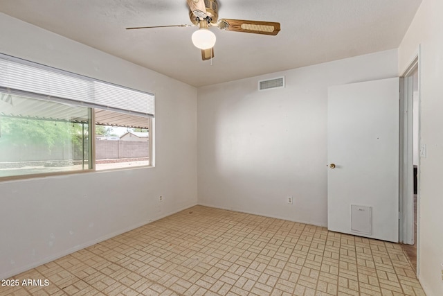 unfurnished room with visible vents, a ceiling fan, and brick patterned floor