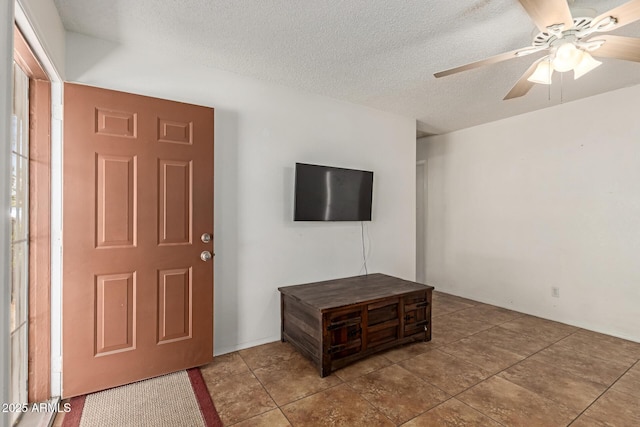 foyer entrance with tile patterned floors, a ceiling fan, and a textured ceiling