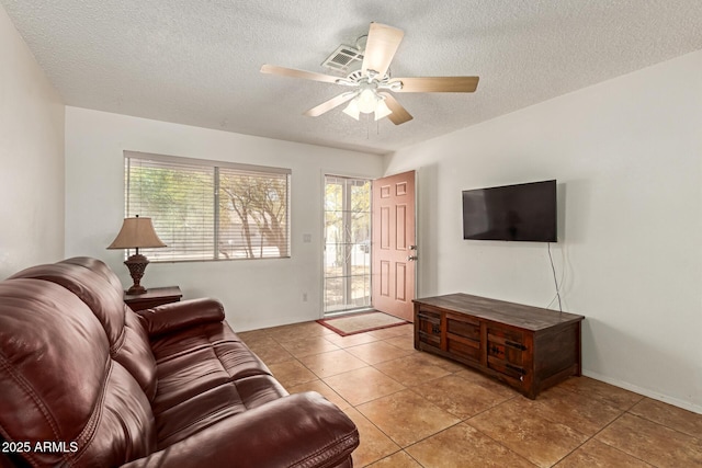 living room featuring light tile patterned floors, a textured ceiling, visible vents, and ceiling fan