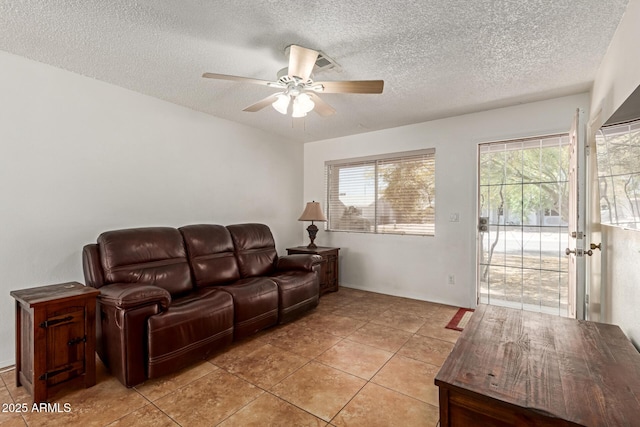 living area with a textured ceiling, baseboards, a ceiling fan, and light tile patterned flooring