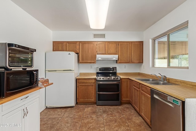 kitchen with visible vents, light countertops, under cabinet range hood, a sink, and stainless steel appliances