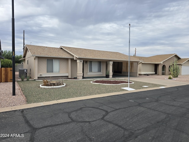 ranch-style home with roof with shingles, stucco siding, fence, a carport, and cooling unit