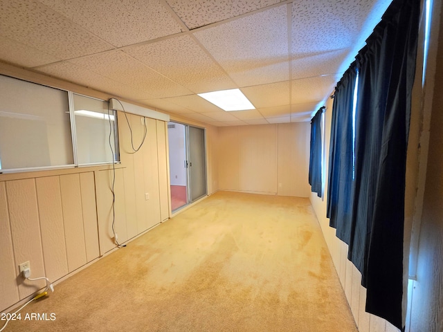 basement featuring light carpet and a paneled ceiling