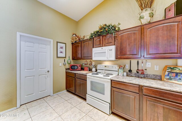 7815 S 22nd Ln, Phoenix, AZ 85041 - kitchen with white appliances, light tile patterned flooring, light countertops, vaulted ceiling, and baseboards