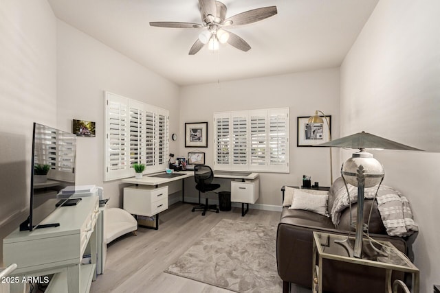 office space with light wood-type flooring, ceiling fan, and baseboards