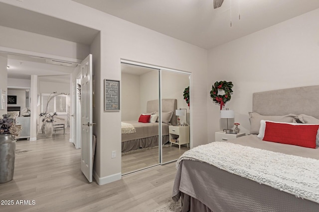 bedroom featuring light wood-style flooring, baseboards, ceiling fan, and a closet