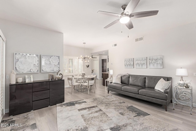 living area with ceiling fan with notable chandelier, visible vents, and light wood-style floors