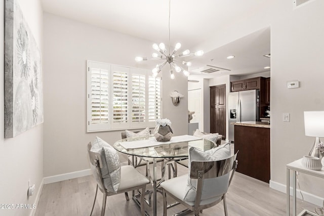 dining area featuring visible vents, a notable chandelier, light wood-style flooring, and baseboards