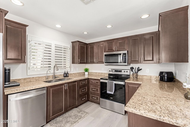 kitchen with stainless steel appliances, recessed lighting, light wood-style flooring, a sink, and dark brown cabinetry