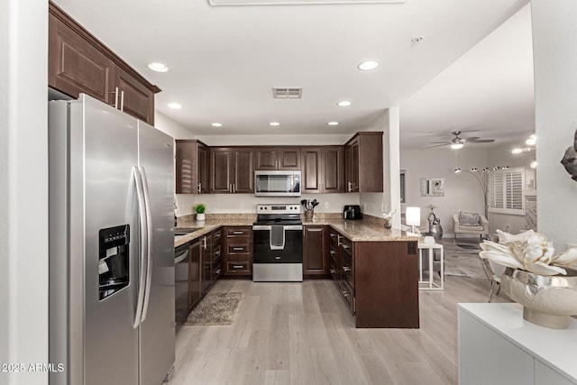 kitchen featuring visible vents, light wood-style flooring, appliances with stainless steel finishes, open floor plan, and dark brown cabinets