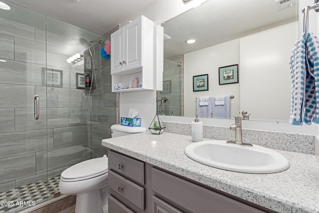 bathroom with vanity, a textured ceiling, a shower with shower door, and toilet