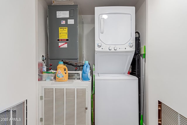 laundry area with stacked washer and dryer and heating unit