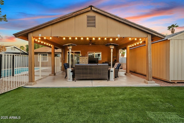 back house at dusk featuring outdoor lounge area, a lawn, and a patio area