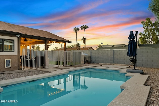 pool at dusk featuring ceiling fan