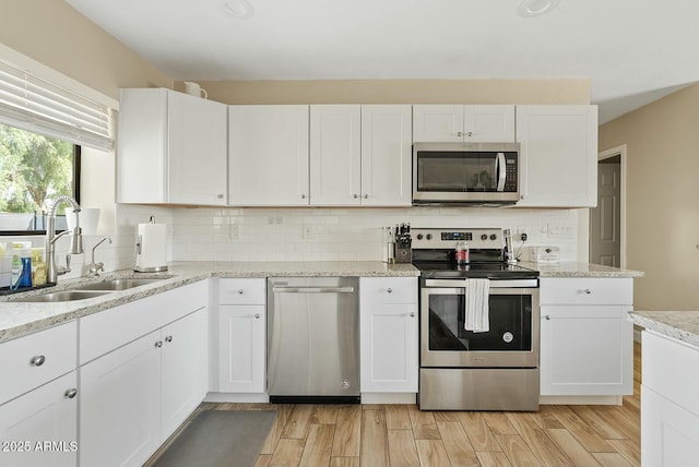 kitchen featuring stainless steel appliances, white cabinetry, and sink