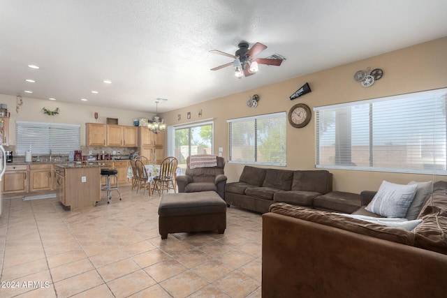 tiled living room featuring ceiling fan with notable chandelier and sink