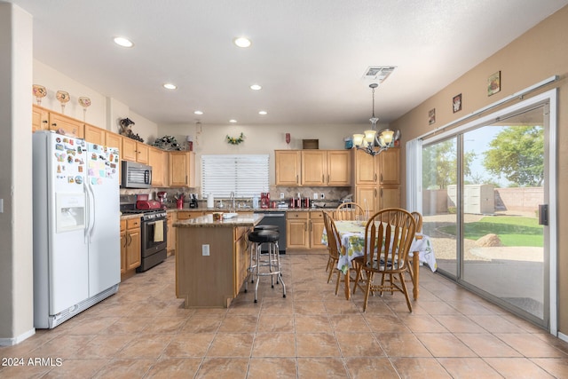 kitchen with a chandelier, tasteful backsplash, a kitchen island, hanging light fixtures, and appliances with stainless steel finishes