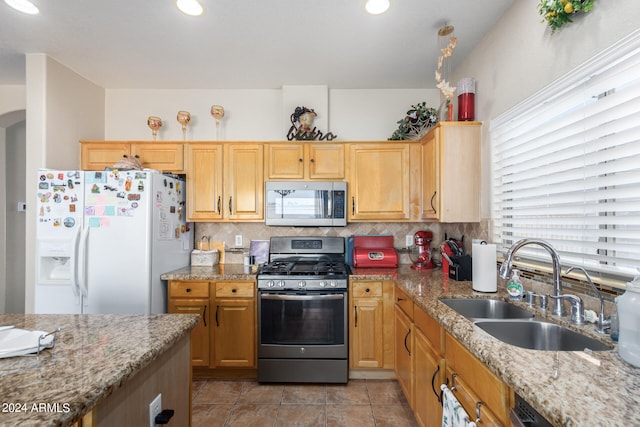 kitchen with light tile patterned flooring, decorative backsplash, sink, light stone counters, and stainless steel appliances