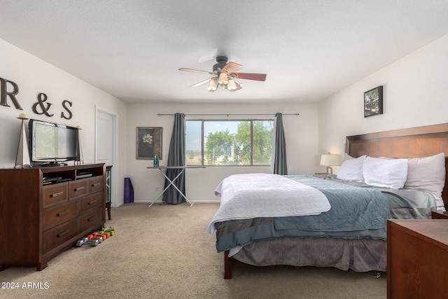 carpeted bedroom with ceiling fan and a textured ceiling