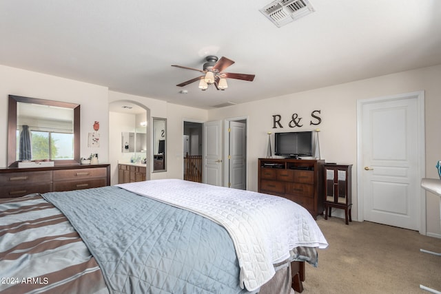 carpeted bedroom featuring ceiling fan and ensuite bath