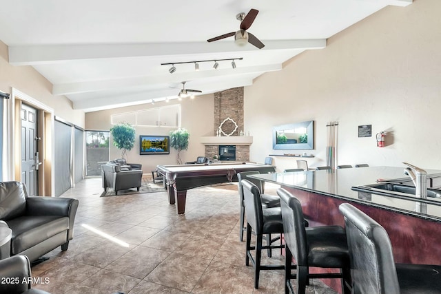 playroom featuring ceiling fan, a large fireplace, lofted ceiling with beams, light tile patterned floors, and pool table