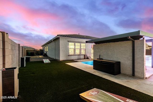 pool at dusk featuring a patio area and a yard