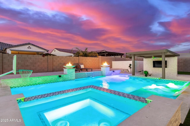 pool at dusk featuring an in ground hot tub, a patio, and a fire pit