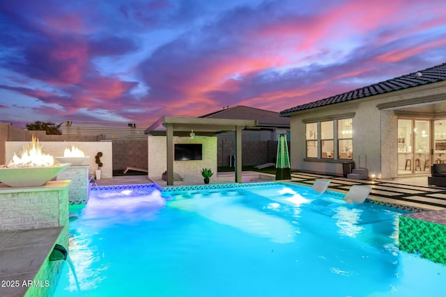 pool at dusk with a patio, an outdoor fire pit, and pool water feature