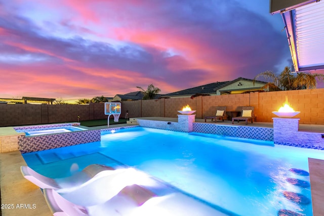 pool at dusk featuring an in ground hot tub