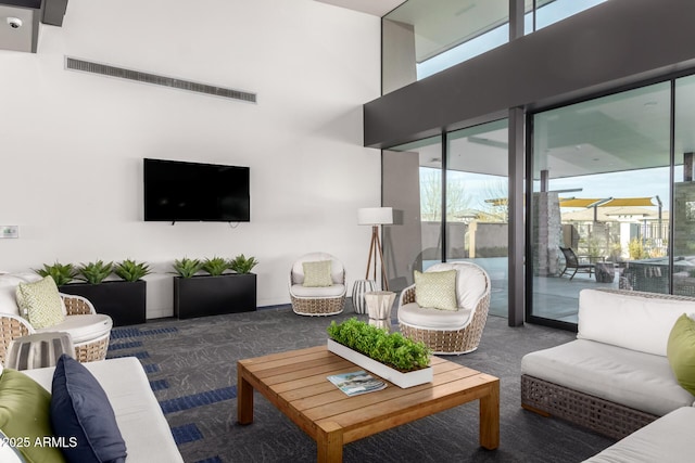 living room featuring a wealth of natural light and dark colored carpet