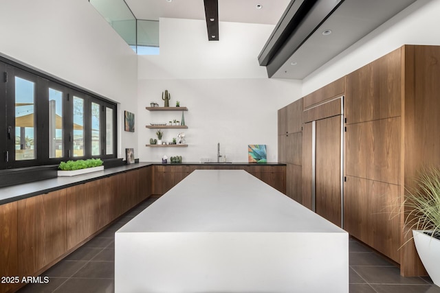 kitchen featuring sink, a center island, a high ceiling, and dark tile patterned floors