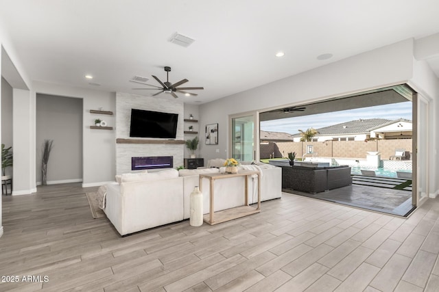 living room featuring ceiling fan and a fireplace