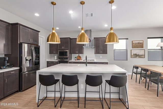 kitchen with dark brown cabinets, decorative light fixtures, a kitchen island with sink, and appliances with stainless steel finishes