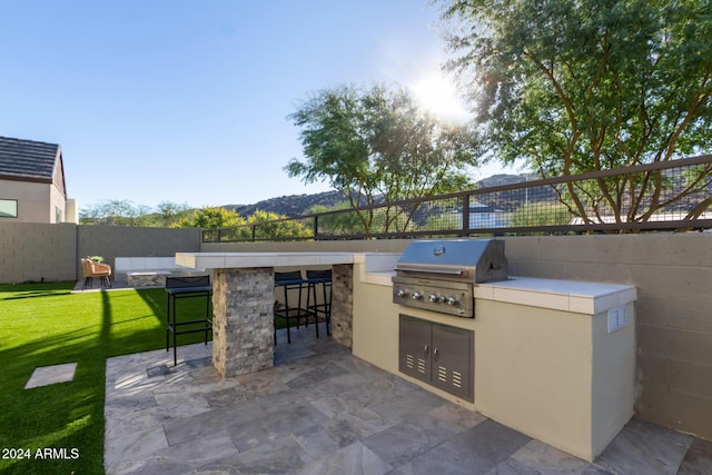 view of patio / terrace featuring a mountain view, an outdoor bar, grilling area, and exterior kitchen