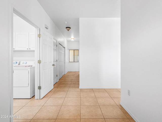 corridor with light tile patterned floors, baseboards, and independent washer and dryer