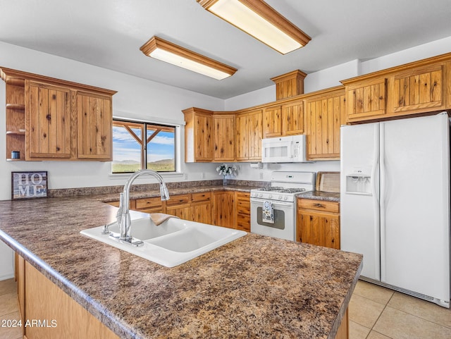 kitchen with dark countertops, white appliances, a peninsula, and a sink