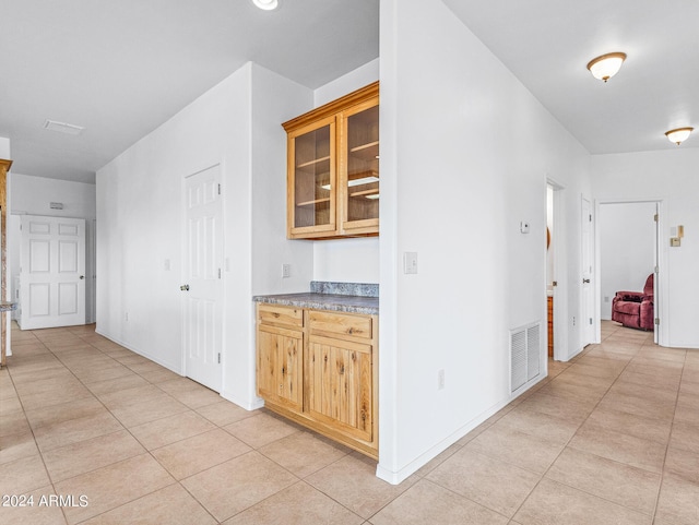 hall featuring light tile patterned floors, visible vents, and baseboards