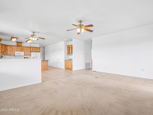 unfurnished living room featuring light tile patterned floors, visible vents, light carpet, and ceiling fan