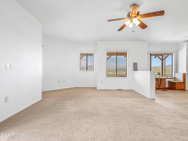 spare room with baseboards, light colored carpet, and a ceiling fan