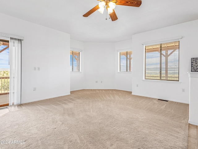 unfurnished room with light carpet, visible vents, baseboards, and a ceiling fan